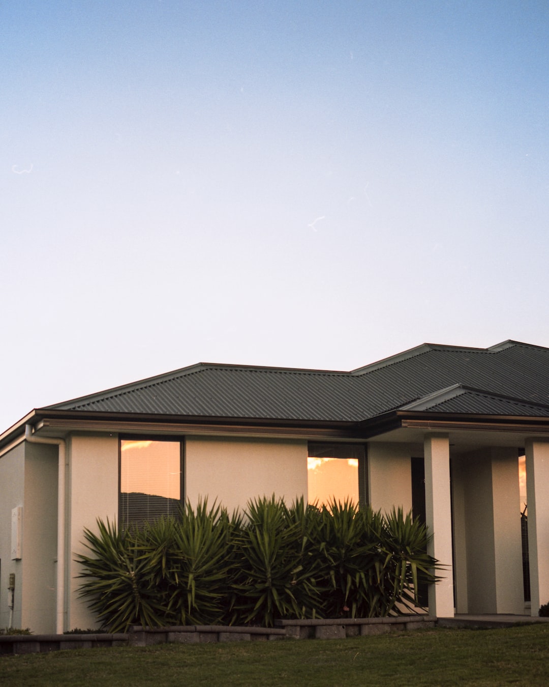 House against cool blue sky with evening sunlight reflected in windows.