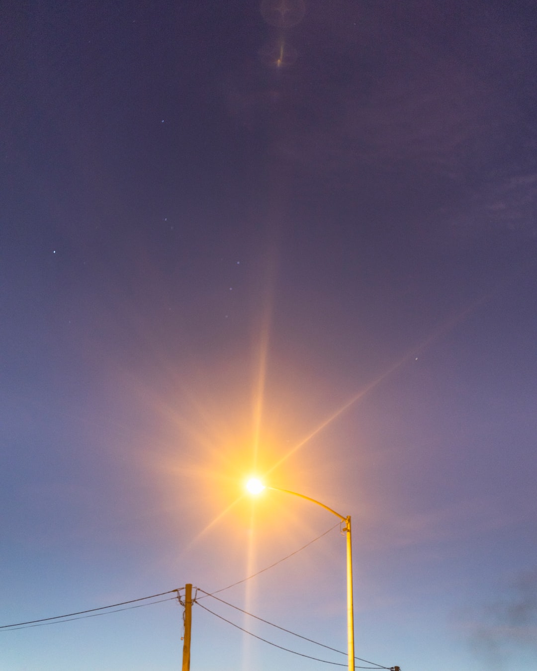 Orange streetlight against the star speckled purple night sky.
