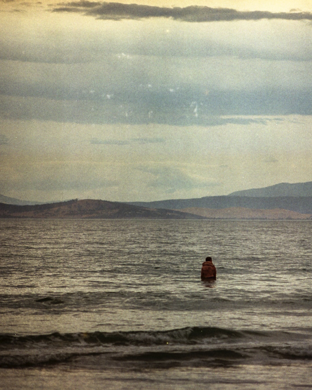 2 swimmers hugging together in the ocean on tattered film.