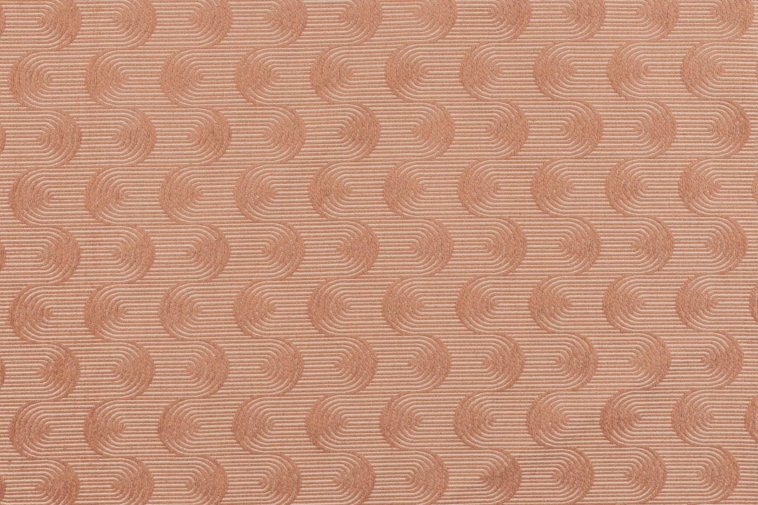 Photo of a coral fabric swatch with repeating wavy swirls. Perfect for computer and phone wallpapers.