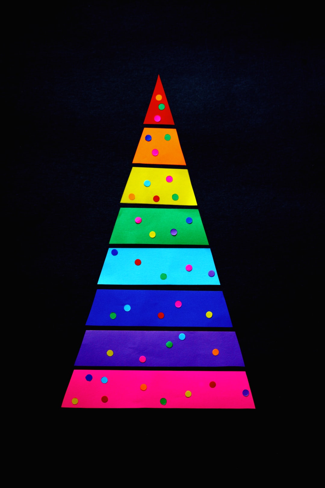 A rainbow Christmas tree background made from colored paper.