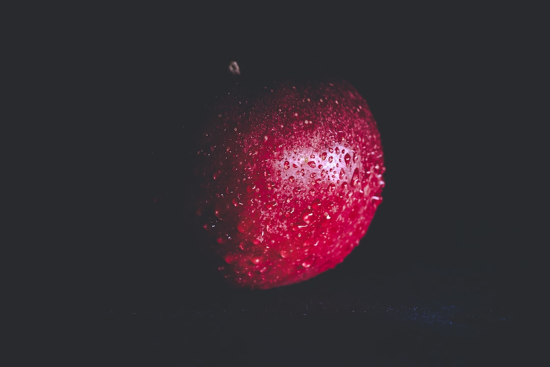 A red colour apple on a black background. Wallpaper material. Mobile wallpaper. Desktop wallpaper.