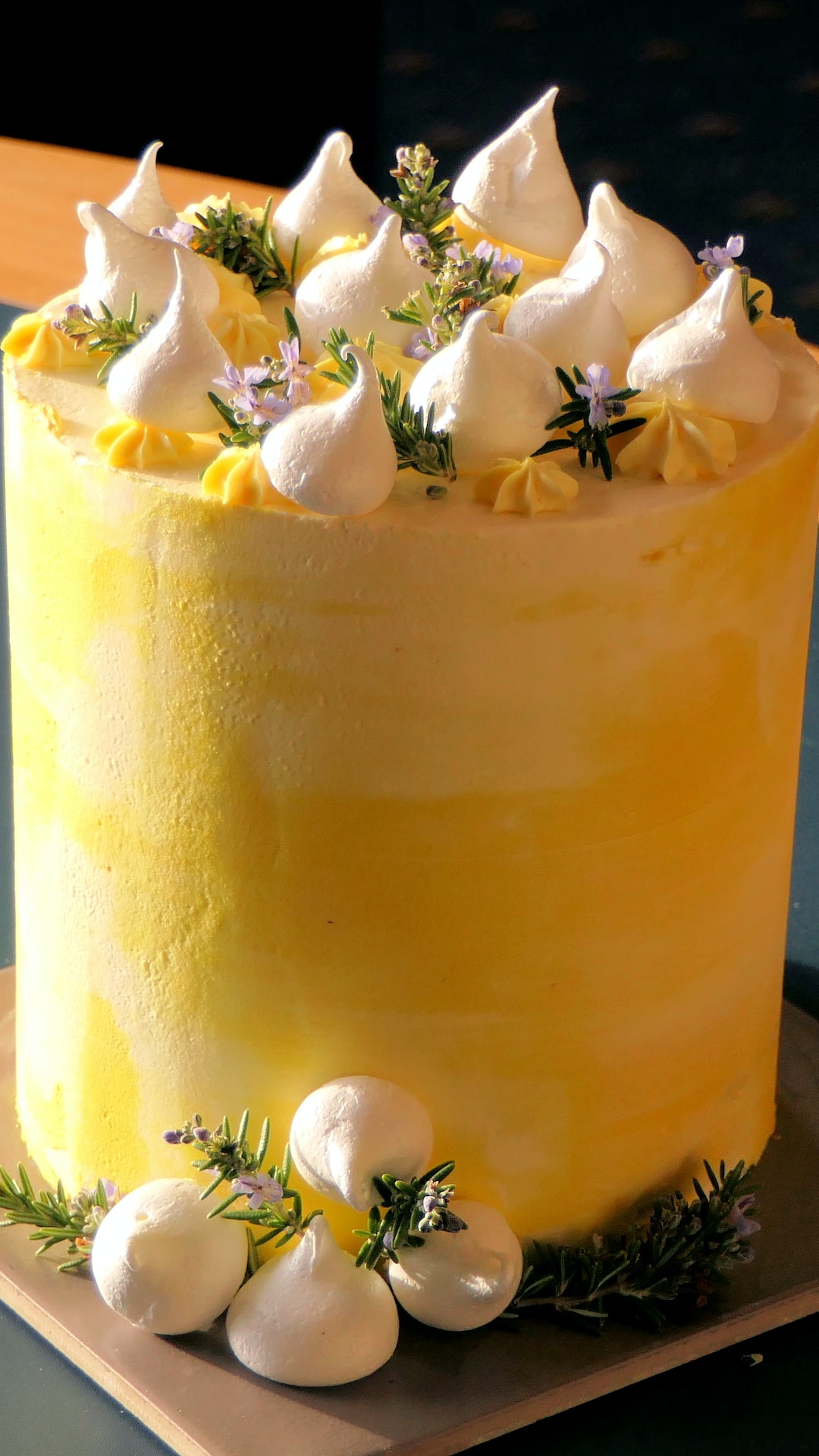 A lemon cake decorated with fresh meringues and rosemary.