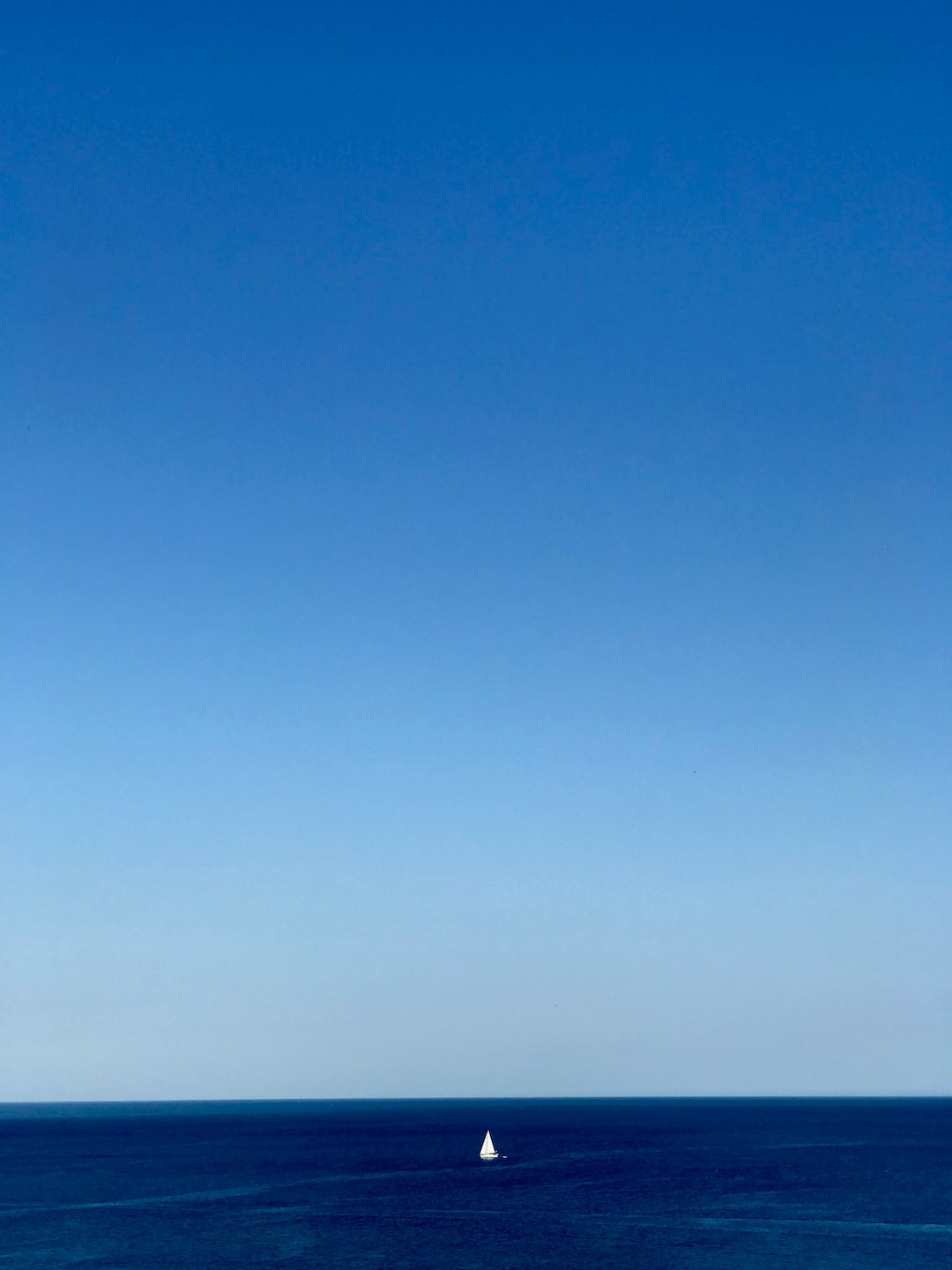 Sardinia summer, blue med sea, blue sky, white sail boat