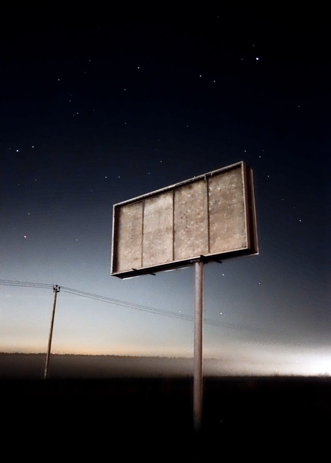 Empty billboard near the foggy road with the view of many stars