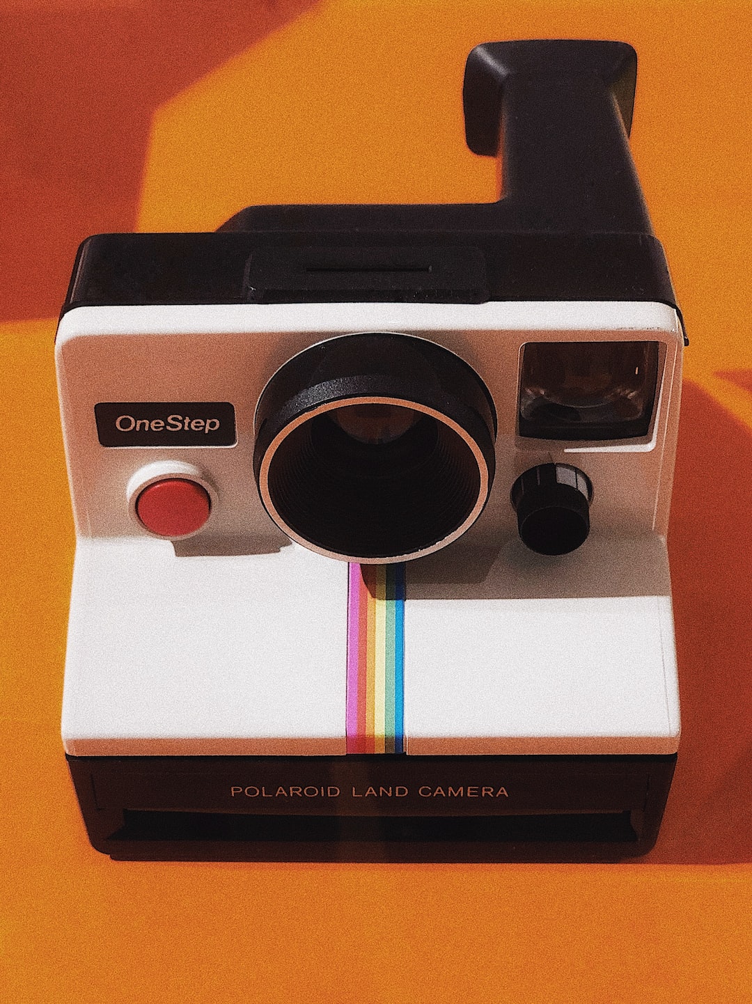 Grandfather of Instant Photography. Minimalistic Vintage Camera with orange background