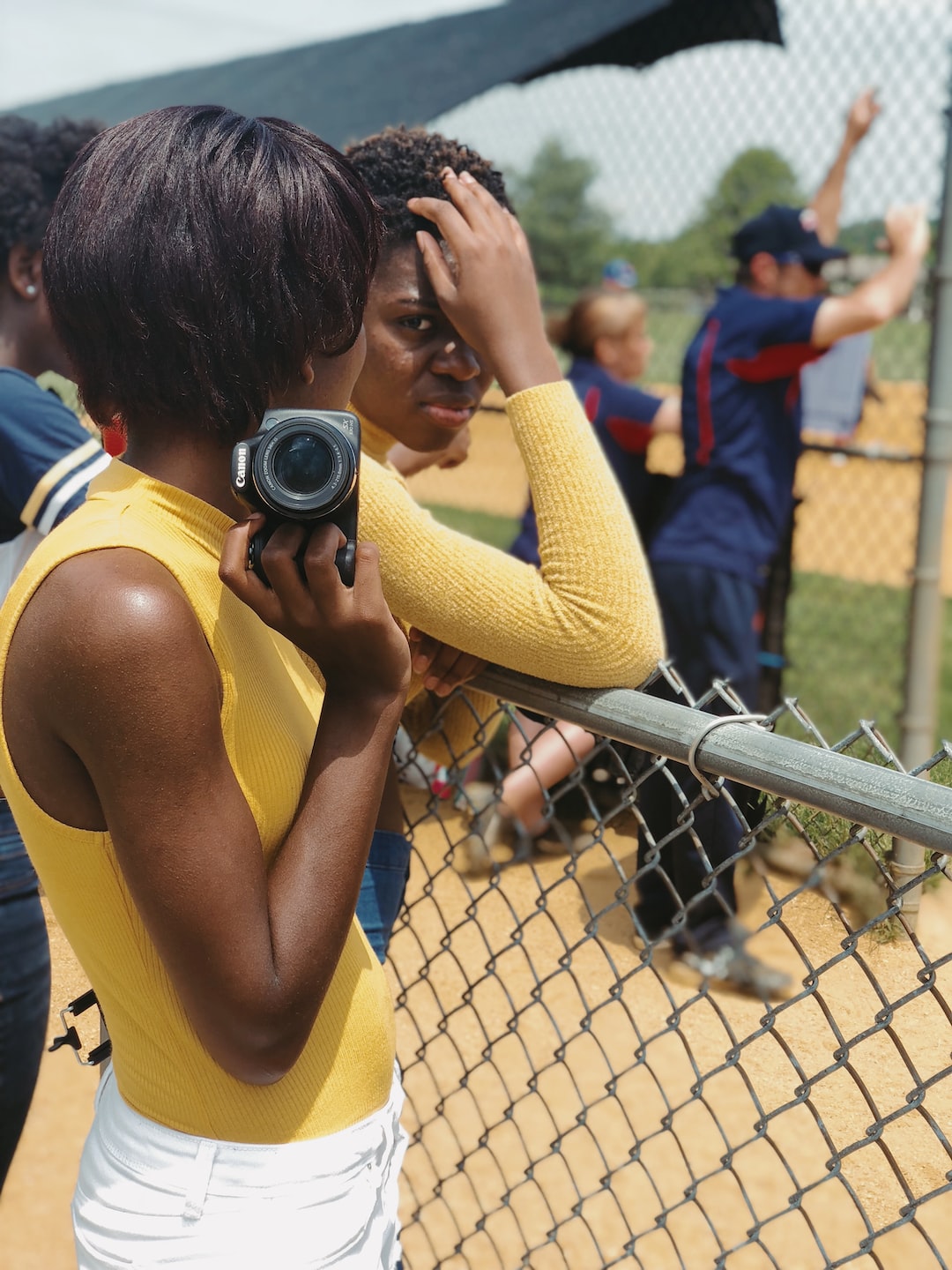 Girl holding camera at a softball game. 