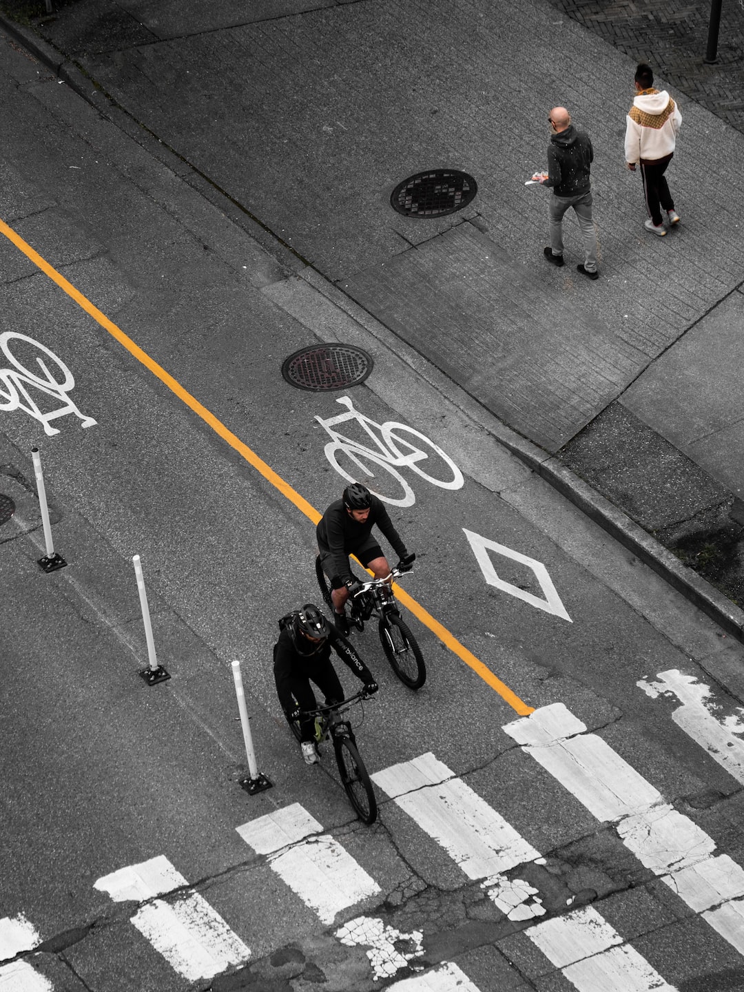 A photo of people on cycling and walking on the street.