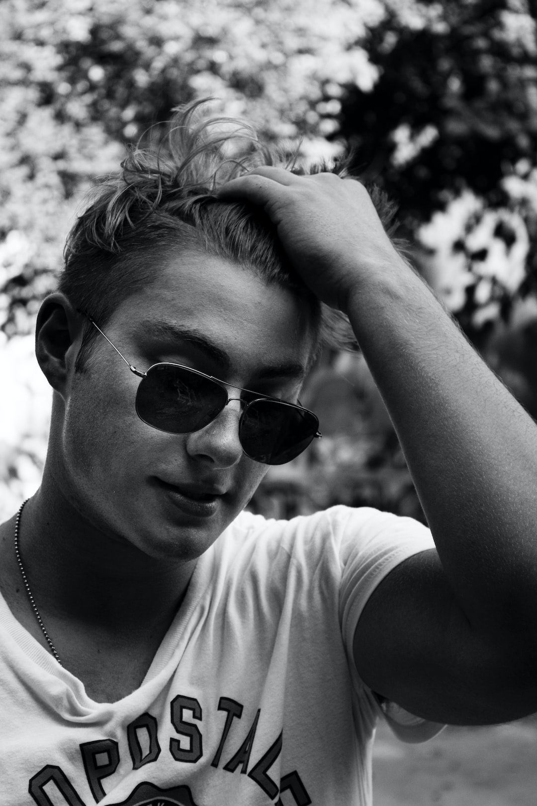 Teenage boy with hand in hair wearing sunglasses portrait.