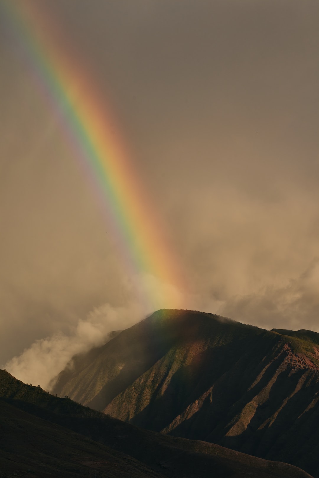 Rainbow and storm clouds over the West Maui Forest Reserve mountains near Lahaina, HI at sunset.