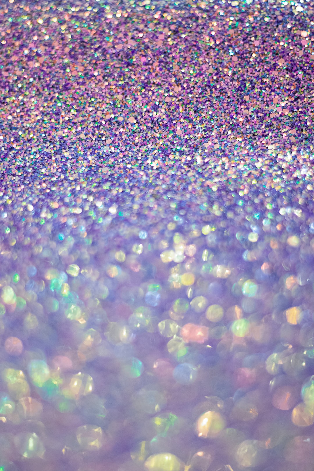 Closeup of purple and pink glitter surface with creamy boke background.