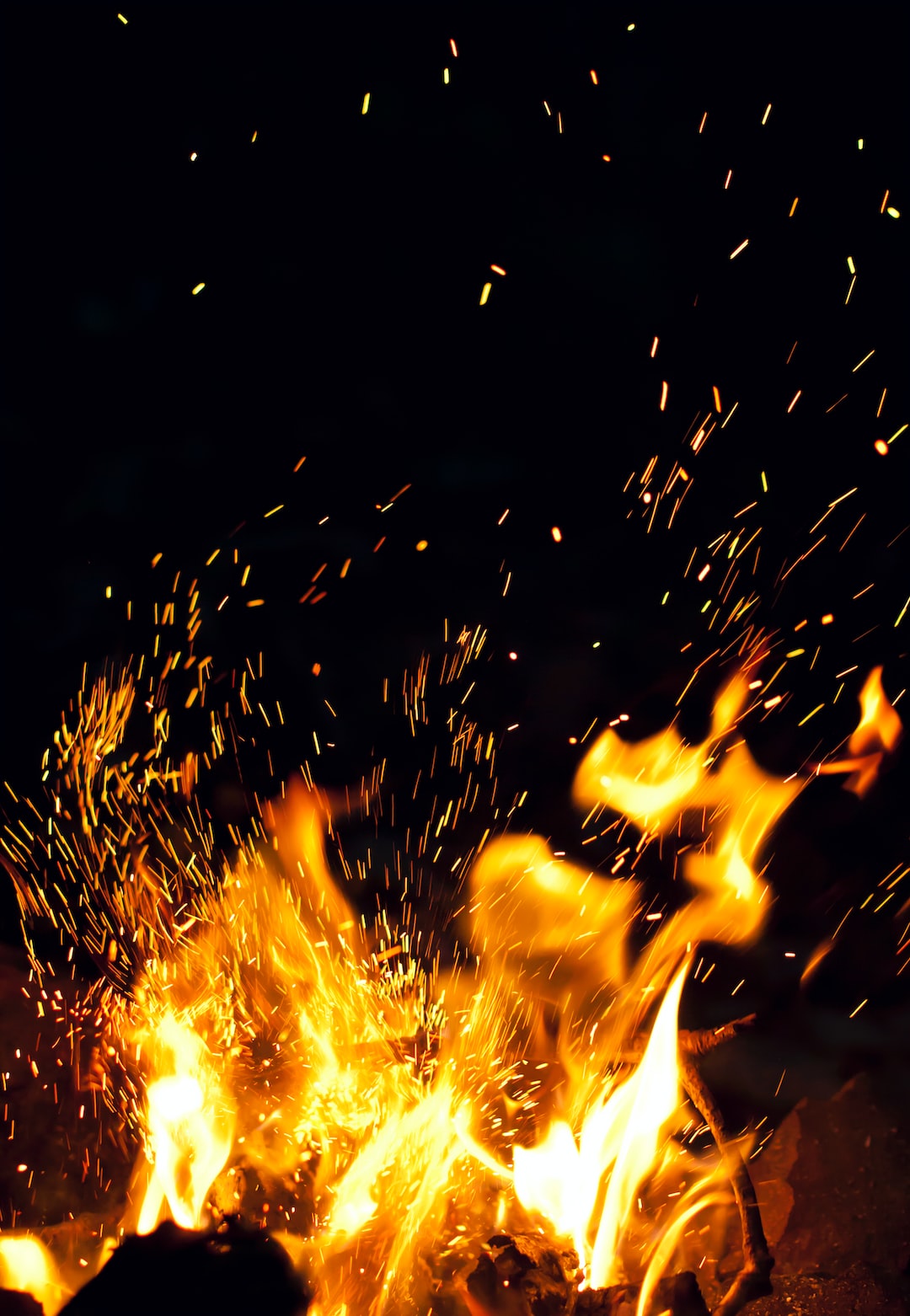 Vertical background with burning flames and sparks for the website, design and social media. Vertical background with a night fire and sparks close-up