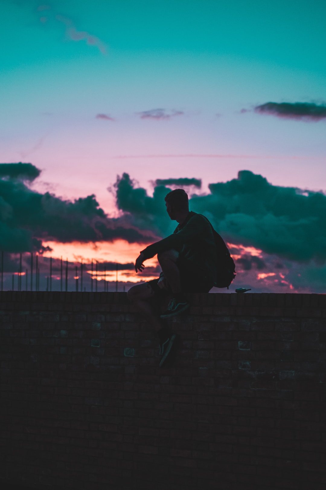 Silhouette of a man sat on a wall