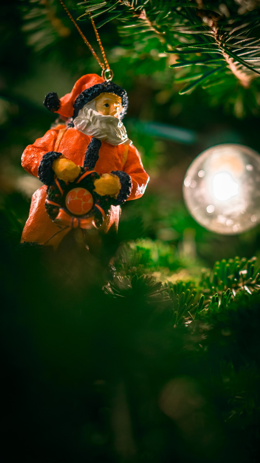 A retro Clemson Tigers Santa ornament hanging on a Christmas tree.