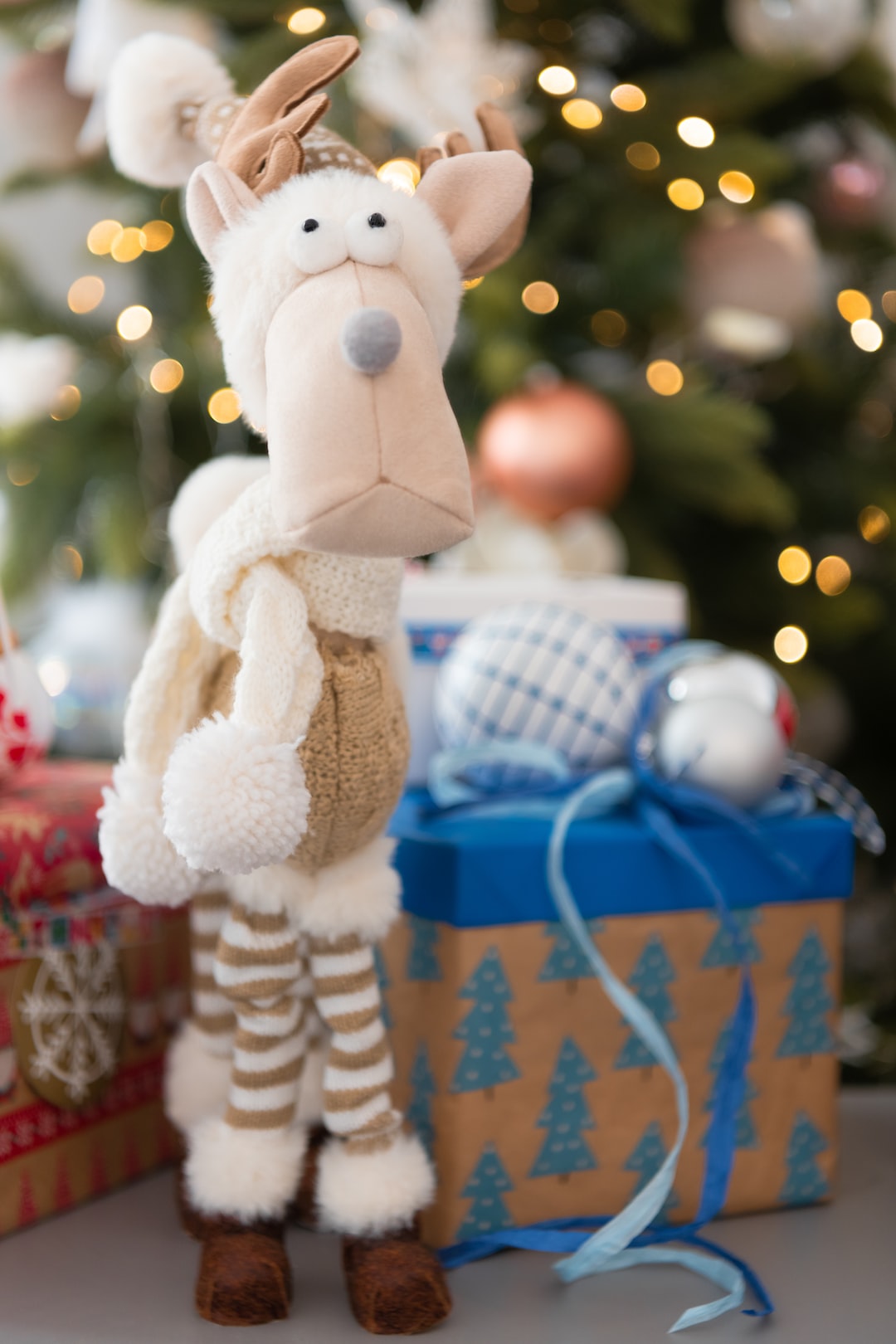 Rentier mit Geschenken vor Weihnachtsbaum / Reindeer with presents in front of a Christmas tree