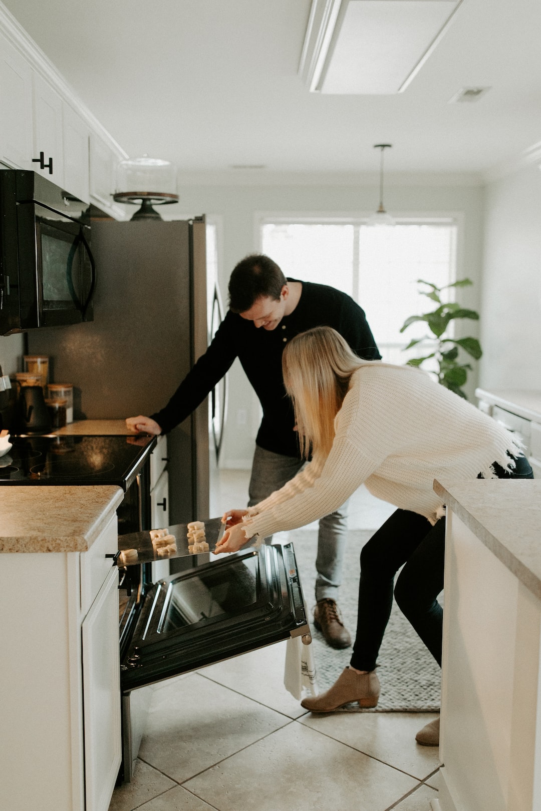 couple baking christmas holiday cookies and putting in the oven