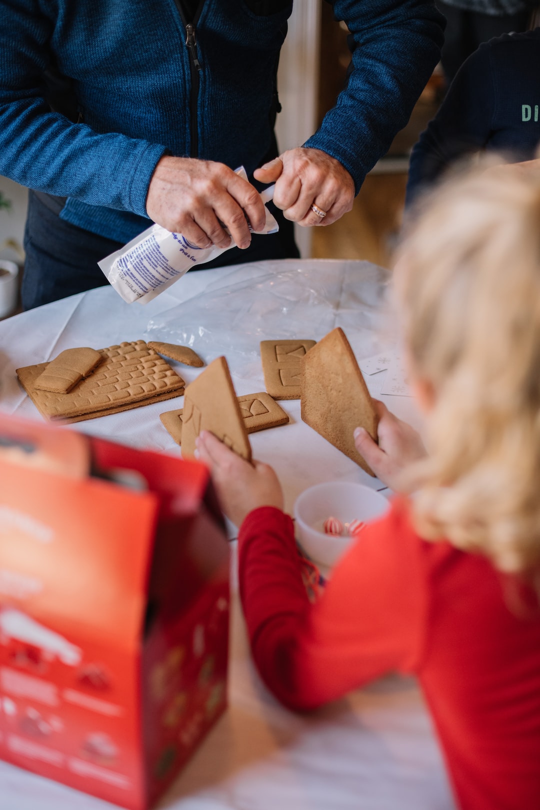 kids with grandparents making a gingerbread house
