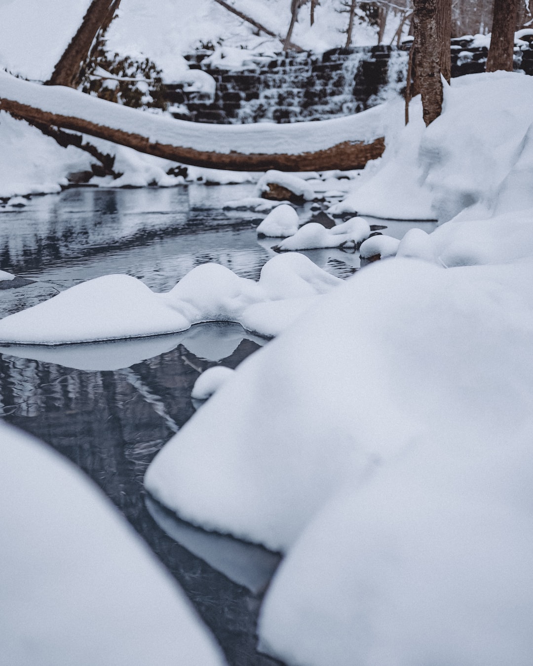 A waterfall in the distance feeds a river as it winds though the winter snow