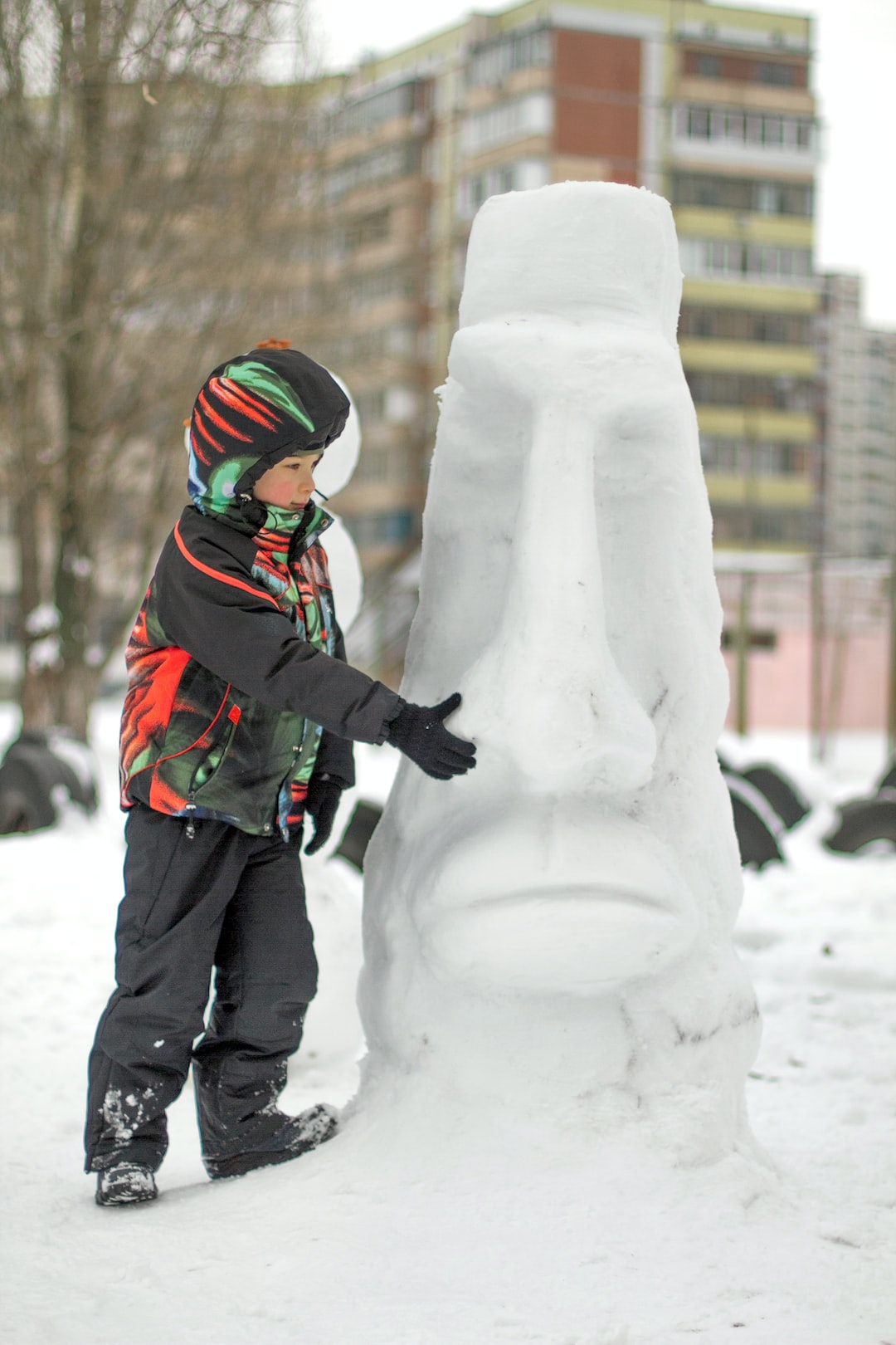 Boy making a winter snowman. An unusul snowman outdoors in snowy winter