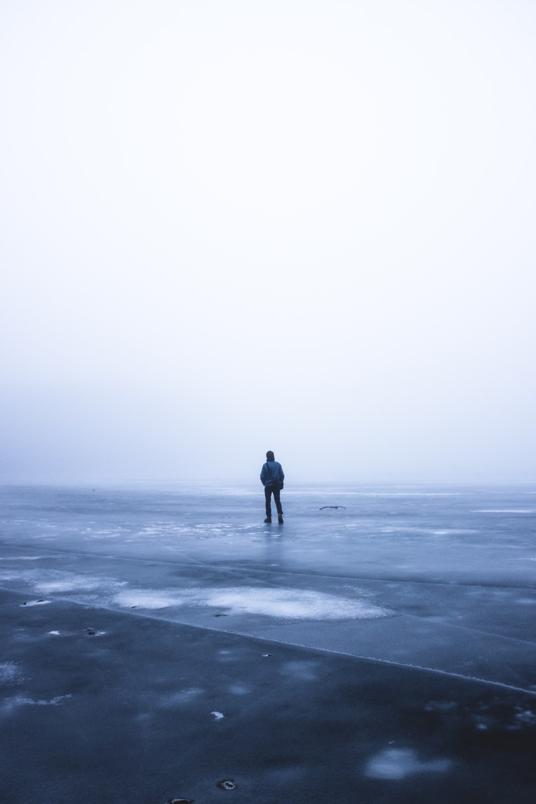 Man walks alone on a frozen lake during Winter.