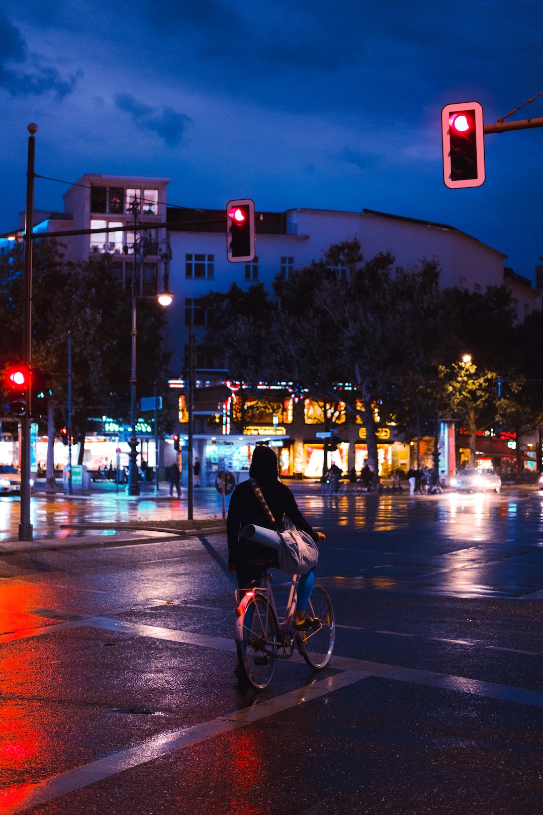 Some girl on a bike waiting at the traffic light in Berlin on a rainy evening.