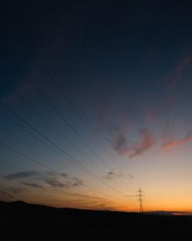 Power lines guiding to a colourful sunset on summer.