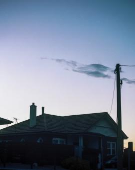 Dark house against bright pink and blue evening sky.