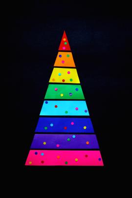 A rainbow Christmas tree background made from colored paper.