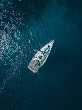 Sailboat shot from above showing the clear blue water of the mediterranean ocean.