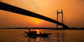 Boat floating on river in evening under the bridge