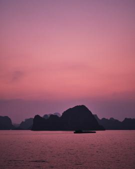 Natural hues seen across these pastel skies beautifully blend with the rocky islands emerging from the sea of Ha Long Bay, Vietnam. 
