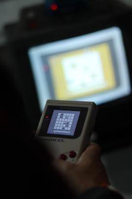 Close up of Game Boy playing game with Sharp SNES TV in the background.