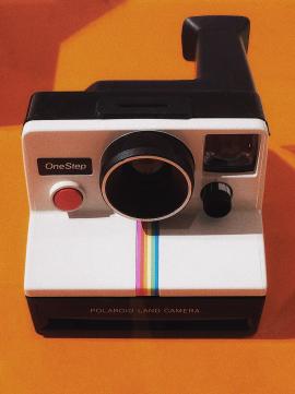 Grandfather of Instant Photography. Minimalistic Vintage Camera with orange background