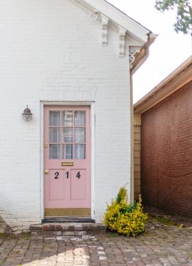 Pink door to a white brick house.