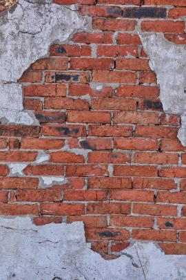 Brick wall with chunks of gray cement and cracks