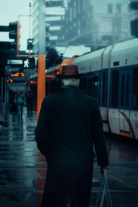 Man in hat walking by train in the rain