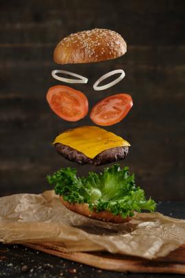 Levitation of delicious burger on wooden background
