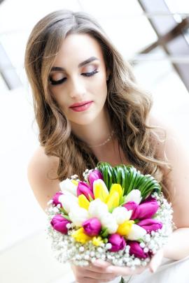 Bride on stairs holding and looking at the flower bouquet.