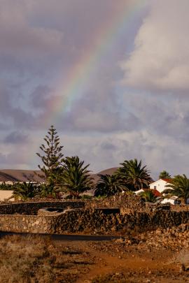 rainbow over hills, palms and houses