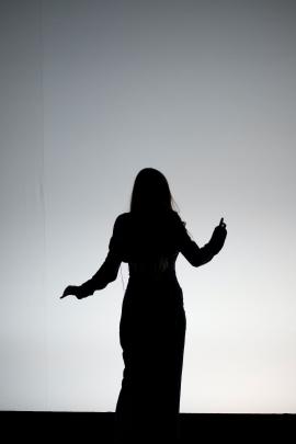 Woman silhouette standing in front of a white wall