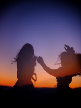 silhuette of two girls dancing during the sunset