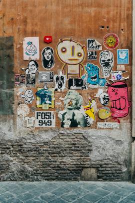 Different wall textures with stickers forming a colorful mural in downtown Rome.