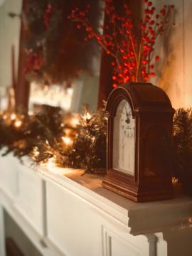 Our fireplace mantel; decorated with faux lighted pine garland, faux red wild berries on their stems, a large mirror, and a faux twig wreath adorned with pine cones and pine sprigs.