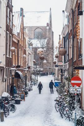 A couple walking in a snowy street in Leiden, the Netherlands, with a church in the back