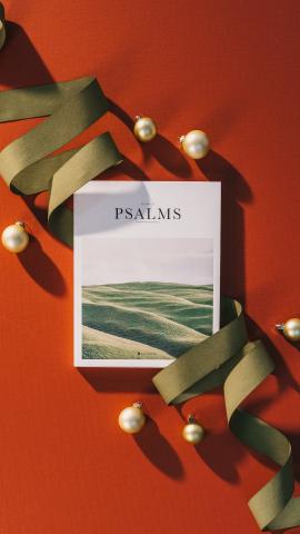 Book of Psalms with Christmas green ribbon and ornaments on a red background