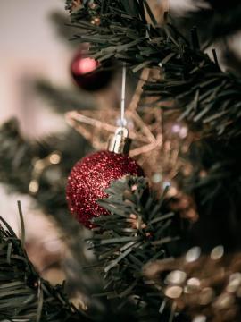 A close-up photo of a red sparkling bauble hanging on a Christmas tree.