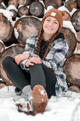 girl smiling at the camera and sitting in the snow