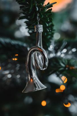 A trumpet Christmas ornament hanging in the Chirstmas tree.