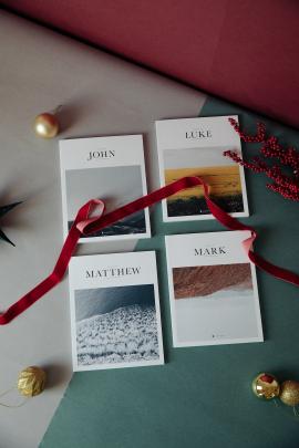 Alabaster Bible books on turquoise, gray, and red background with Christmas gold ornaments and red velvet ribbon