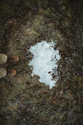 Hikers boots by an icy puddle